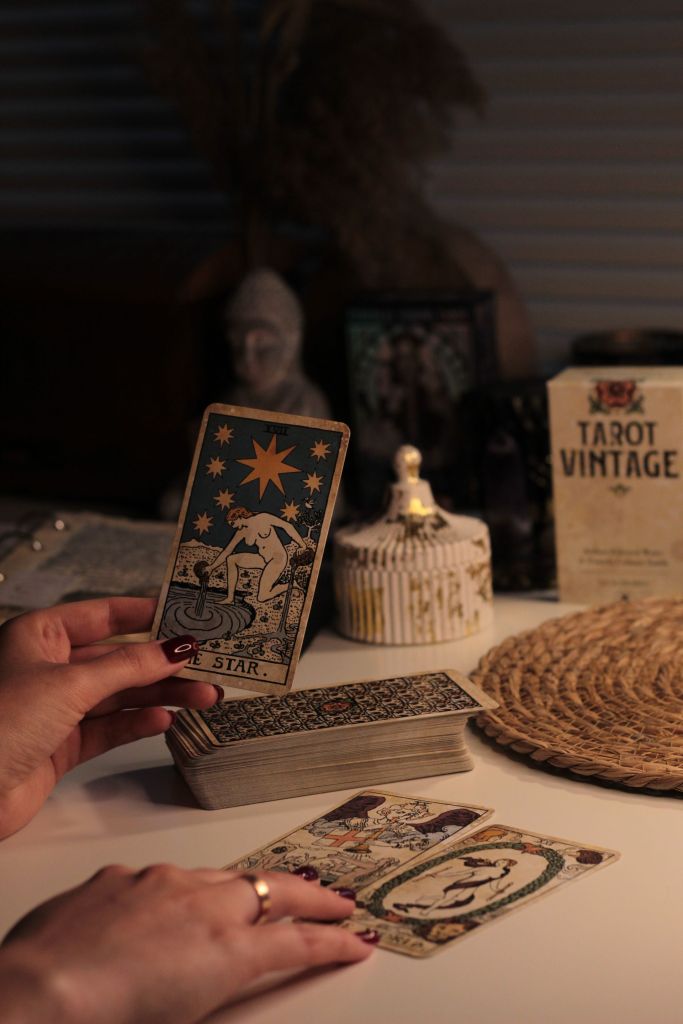 Eine Hand legt Tarotkarten im Kerzenlicht